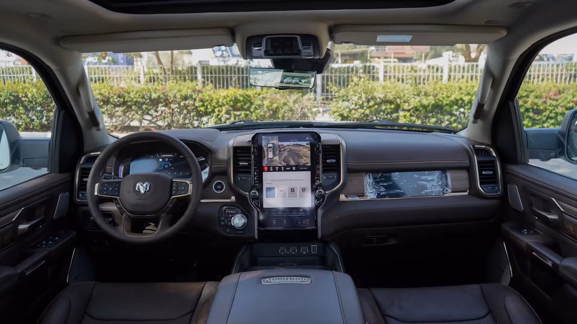 Interior view of the 2026 Ram 1500 Longhorn dashboard, featuring a large vertical touchscreen, digital driver display, real wood accents, and premium leather.