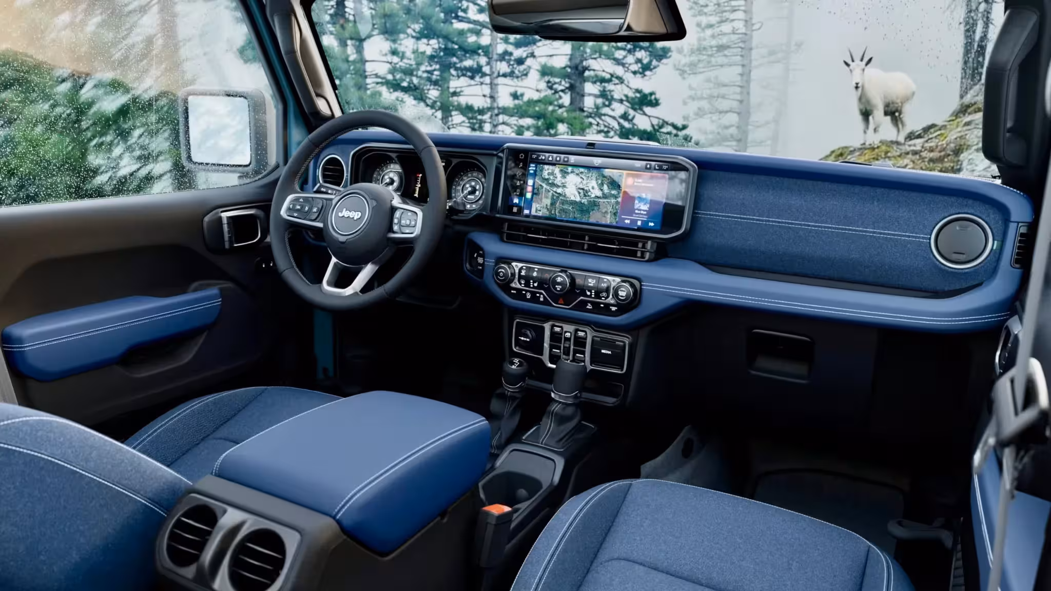Interior view of the 2026 Jeep Wrangler Rockslide, showcasing Indigo Blue dashboard and door accents with silver stitching, and Jean Blue cloth seats.