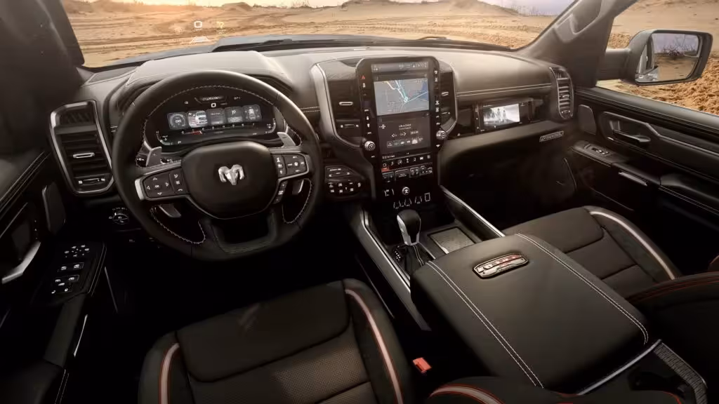 Interior of the 2026 Ram 1500 Rebel X Crew Cab, showing the premium cabin with dual Uconnect screens, digital gauge cluster, console shifter, and red-stitched seats.