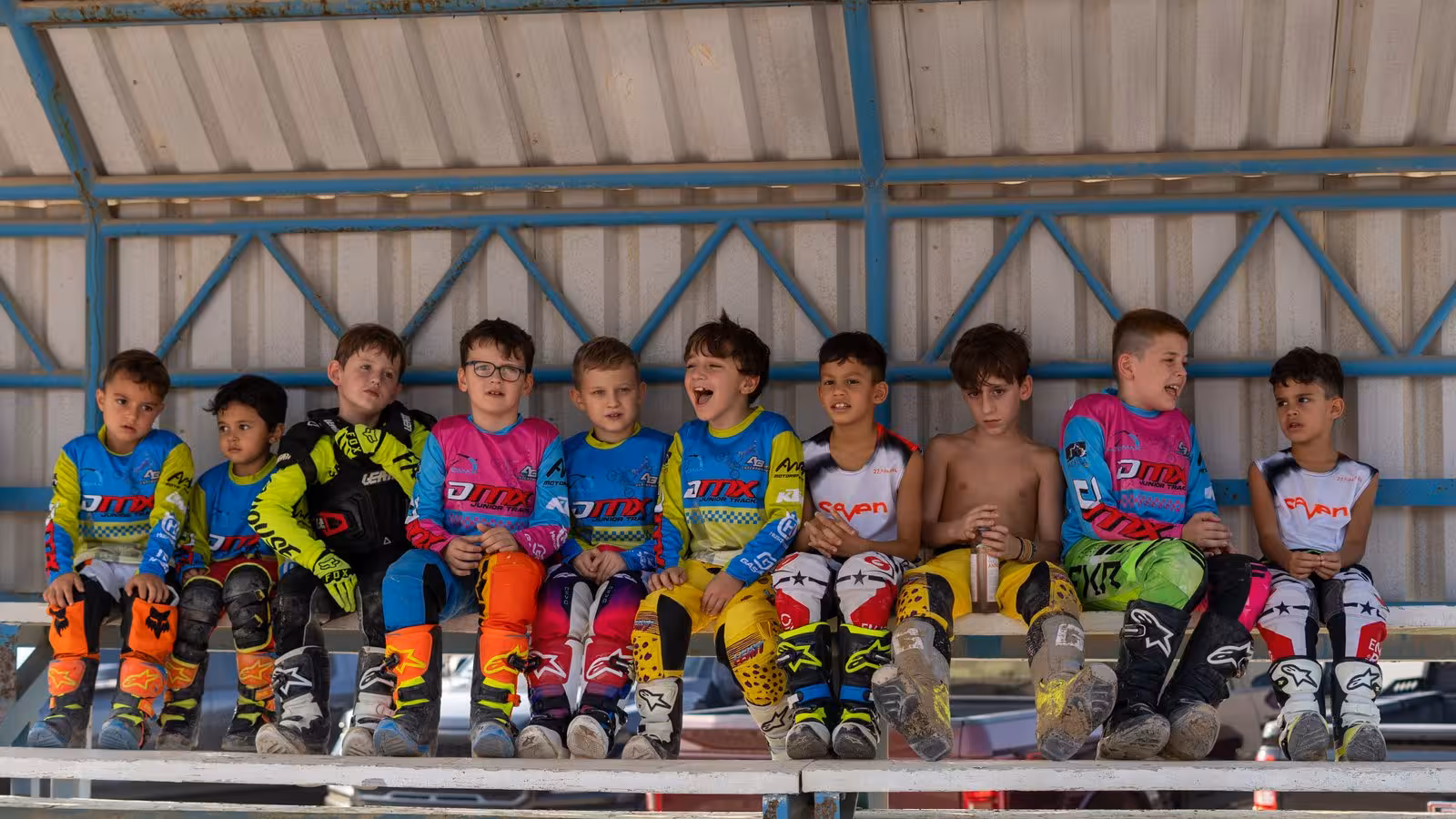 Motocross rider in a blue, yellow, and pink suit on an orange KTM dirt bike, number 666, racing on a sandy DMX track.