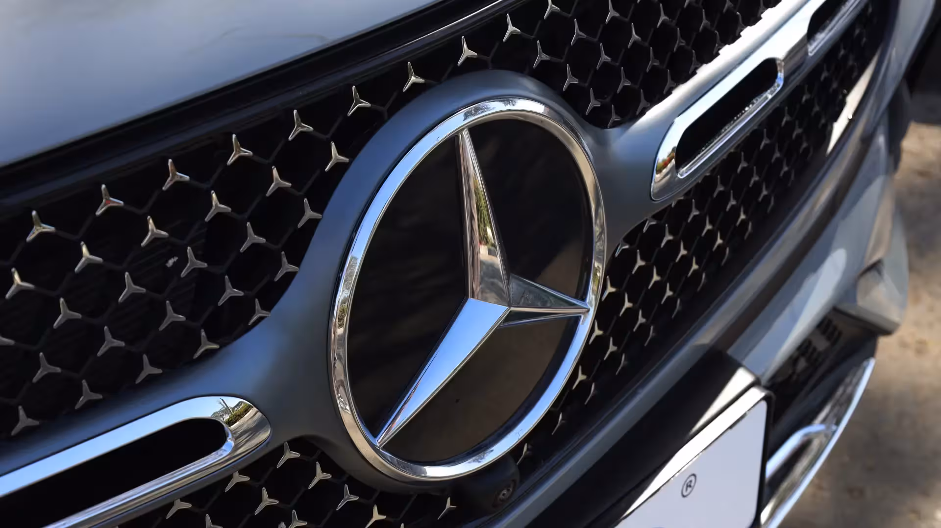 Close-up detail of the chrome Mercedes-Benz three-pointed star emblem centered on the intricate 'diamond' pattern front grille of the GLC Coupe.