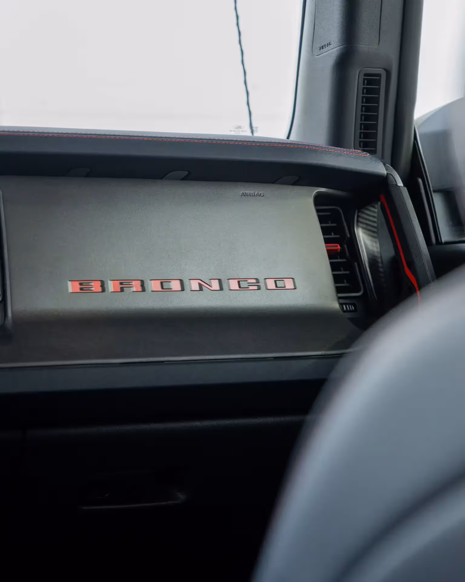 Close-up of the passenger side dashboard with 'BRONCO' lettering in red and red accents around the air vent.