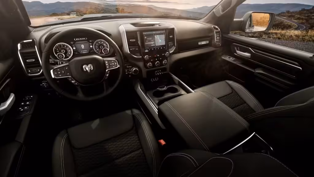 Interior view of the 2026 Ram 1500 BackCountry, showing black vinyl bucket seats, steering wheel, digital cluster, and large infotainment screen.