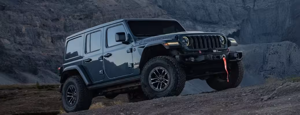 Dark grey 2026 Jeep Wrangler Rubicon Unlimited ascending a rocky trail with Xtreme 35 Tire Package.
