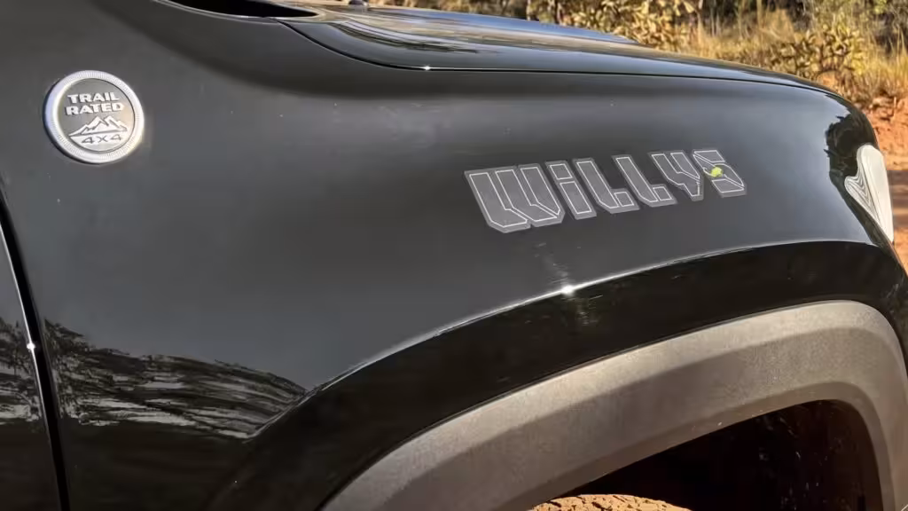 Close-up of the fender of a dark green 2027 Jeep Renegade Willys 4x4 Turbo, clearly showing the 'TRAIL RATED 4X4' badge and 'WILLYS' lettering.