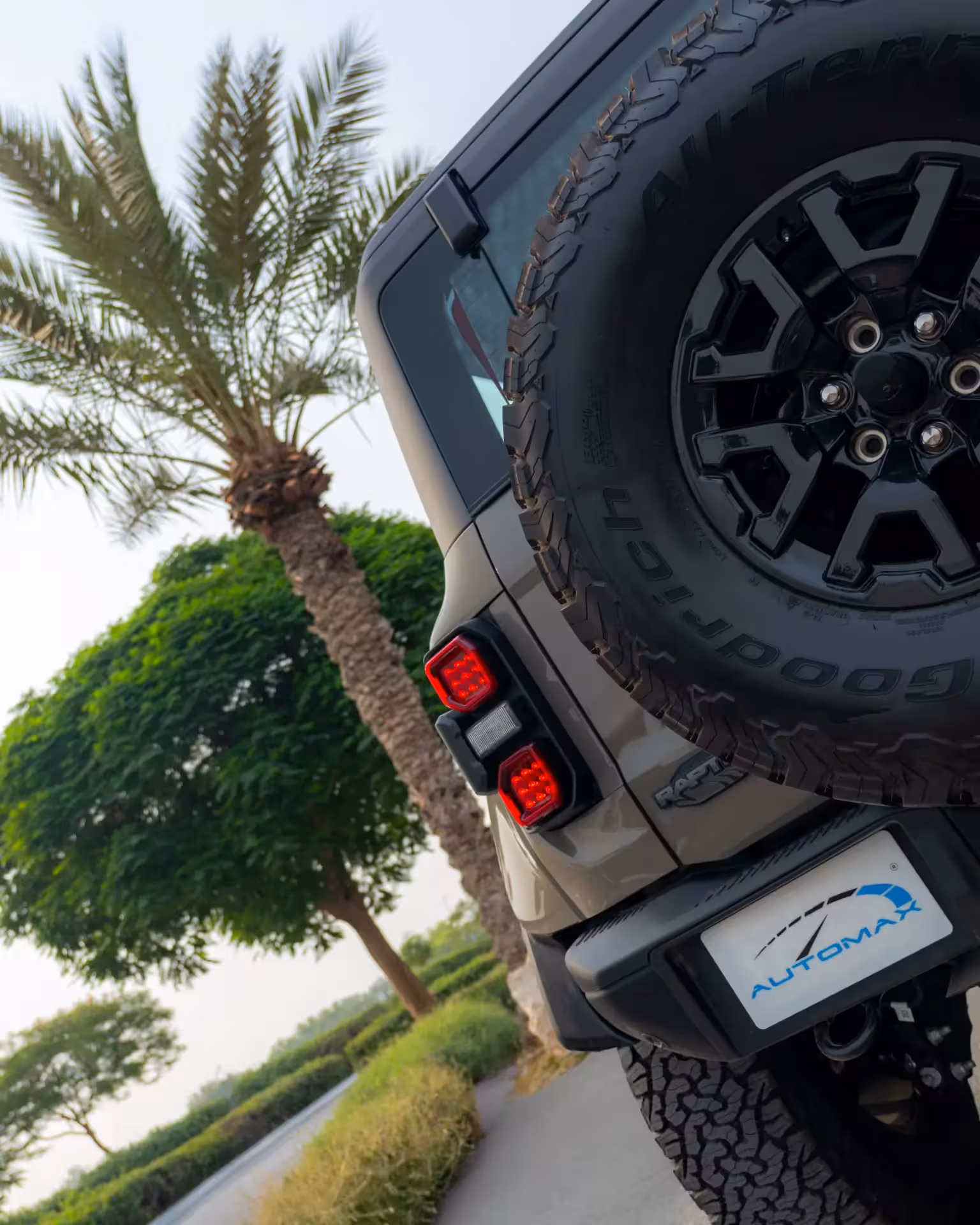 Dynamic low-angle front view of a dark green/khaki 2025 Ford Bronco Raptor, emphasizing its wide stance and large off-road tires.