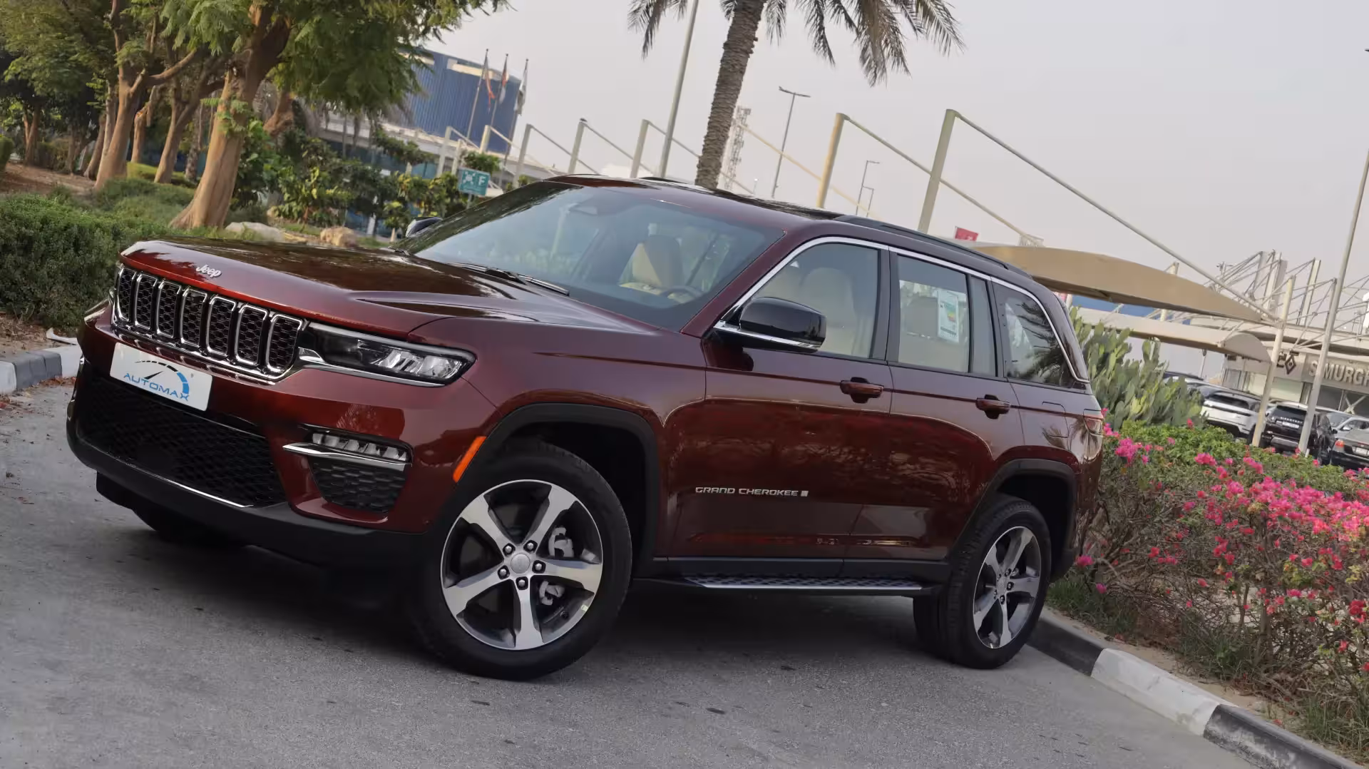Front three-quarter view of a deep red 2025 Jeep Grand Cherokee Limited, showcasing its iconic grille and sleek LED headlights.