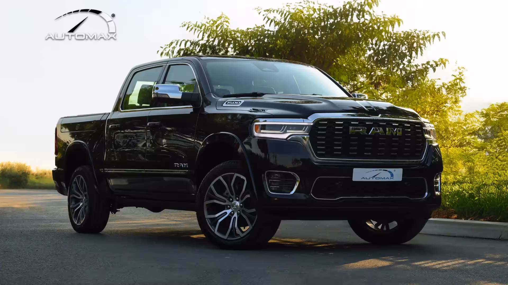 Front three-quarter view of a black 2026 Ram 1500 Tungsten luxury pickup truck, parked with lush green foliage in the background.